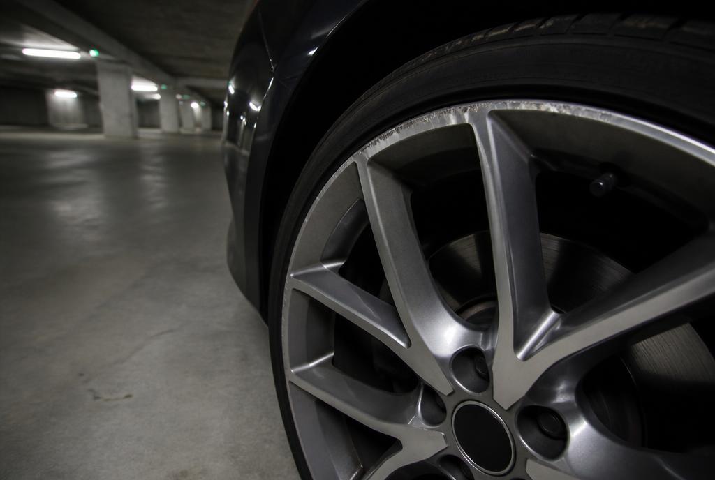 Scuffed alloy wheel on a car in a concrete car park